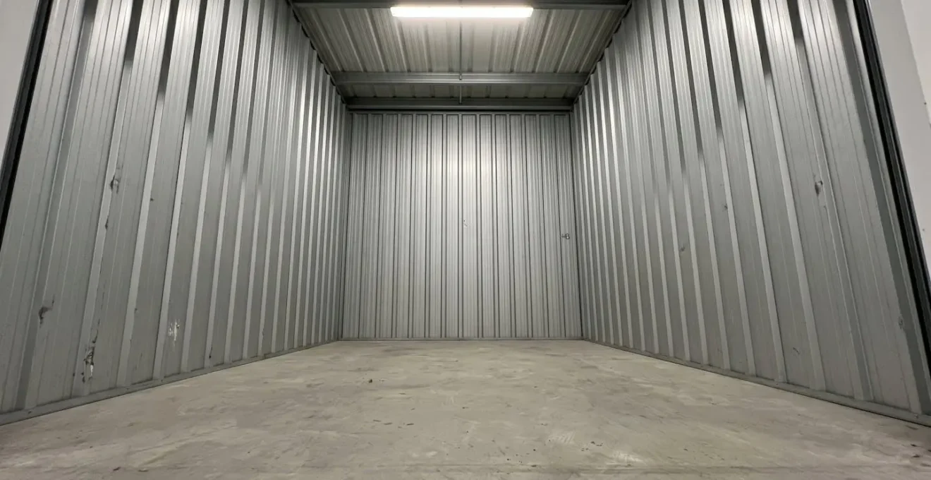 Vue en contre-plongée de l'intérieur d'un box de stockage vide montrant la hauteur sous plafond avec des murs blancs propres et un sol en béton lisse